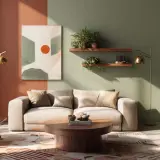 Salon moderne avec canapé clair, fauteuil en cuir, table basse en bois et mur bicolore, dont une partie est peinte en **couleur terracotta**.
