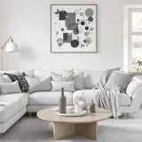 Un salon gris et beige invitant, parfait pour le cocooning. Un grand canapé blanc est orné de coussins douillets et d'un plaid. Une table basse en bois clair complète l'ensemble.