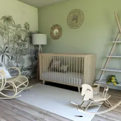 Une chambre bébé mixte avec un mur jungle, berceau en bois, fauteuil rotin, cheval à bascule. Une belle idée déco !
