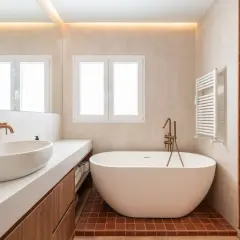Salle de bain moderne avec baignoire îlot. L'éclairage indirect au plafond et la lumière naturelle par la fenêtre aident à comment éclairer une salle de bain.