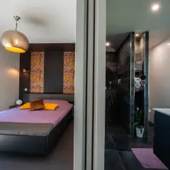 Chambre moderne avec lit violet et salle de bain attenante. La **taille suite parentale** est idéale pour un confort optimal.