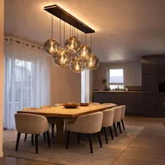 Une table à manger moderne avec des chaises confortables, éclairée par un lustre sphérique, une vraie tendance luminaire.