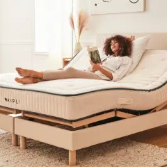 Femme lisant sur un lit électrique réglable. Avantage inconvénient lit électrique : confort personnalisé pour la détente.
