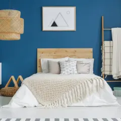 Une chambre bleu et beige avec un lit douillet, une lampe en rotin et une décoration murale minimaliste.