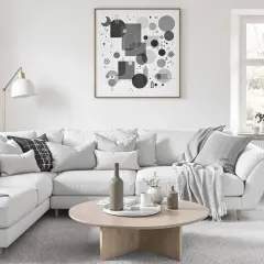 Un salon gris et beige invitant, parfait pour le cocooning. Un grand canapé blanc est orné de coussins douillets et d'un plaid. Une table basse en bois clair complète l'ensemble.