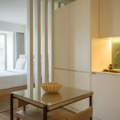 Un studio aménagé pour créer une chambre et une cuisine fonctionnelle. Un lit douillet fait face à une fenêtre, tandis qu'une kitchenette moderne est séparée par des cloisons.