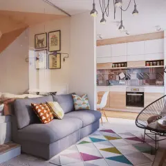 Salon moderne avec canapé gris, lit surélevé, cuisine et tapis géométrique coloré.