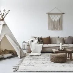 Un coin jeux dans un petit salon avec une tente tipi, un canapé confortable et un tapis douillet. Une idée parfaite pour un espace enfant cosy.
