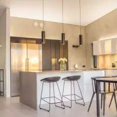 Cuisine lumineuse couleur, avec îlot central, tabourets, réfrigérateur en inox et armoires murales.