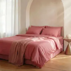 Lit rose avec couvre-lit et coussins. Le polycoton, malgré son aspect doux, peut avoir un inconvénient : il retient la chaleur.