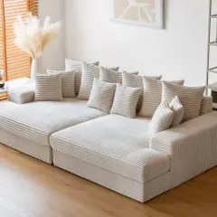 Canapé modulable blanc côtelé, offrant une grande profondeur pour un confort optimal. Des coussins moelleux invitent à la détente.