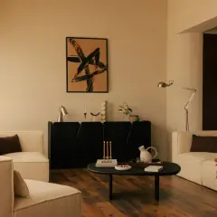 Salon moderne avec fauteuils blancs, buffet noir, tableau abstrait et table basse. Une ambiance chaleureuse pour une deco interieur tendance.
