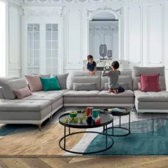 Un salon moderne et lumineux avec un canapé modulable gris, des coussins colorés et un tapis graphique. Une déco séjour tendance pour une famille.