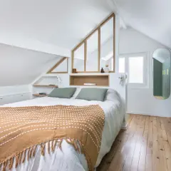 Suite parentale sous comble avec salle de bain et dressing. Un lit douillet, des rangements intégrés et une verrière style verrière d'atelier apportent charme et fonctionnalité.