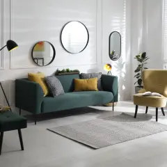 Un salon moderne avec un canapé vert, un fauteuil jaune et plusieurs miroirs derrière le canapé.