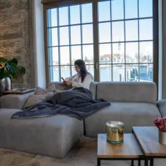 Femme en bonne position assise canapé, profitant de son téléphone avec une vue sur l'eau.