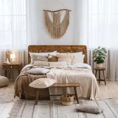 Chambre déco bohème avec un lit en bois, des coussins texturés, des plantes vertes et un macramé mural. Ambiance douce et naturelle.