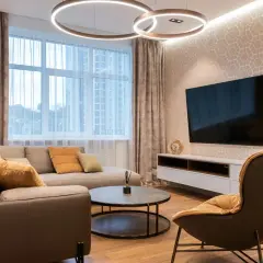 Salon moderne avec canapé, fauteuil, table basse et TV. Le **plan éclairage** met en valeur les suspensions circulaires et l'applique murale.