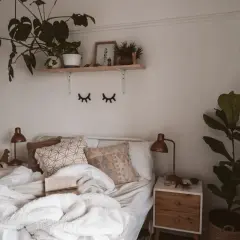 Lit, douillet et plein de verdure, ce lit invite à la détente. Une belle **déco chambre nature** avec des plantes luxuriantes et des coussins texturés.