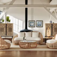 Ambiance cosy avec cette idée déco salon rotin : fauteuils enveloppants, canapé, table basse et meubles de rangement en rotin naturel.