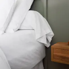 Un lit blanc immaculé avec un drap housse bien ajusté, prêt pour une nuit paisible. C'est quoi un drap housse ? C'est ce qui protège votre matelas.