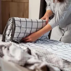 Une personne applique la méthode de pliage couette Marie Kondo pour ranger une housse de couette à carreaux noirs et blancs.