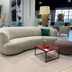 Un canapé courbé et un fauteuil rouge, illustrant la différence entre canapé et fauteuil, dans un showroom de meubles.