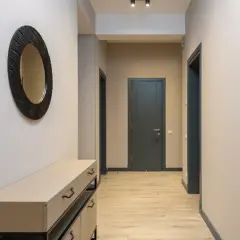 Un couloir sans fenêtre peut être lumineux avec des murs clairs et un grand miroir. Les portes sombres créent un contraste élégant.
