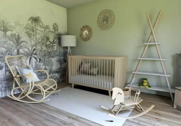 Une chambre bébé mixte avec un mur jungle, berceau en bois, fauteuil rotin, cheval à bascule. Une belle idée déco !