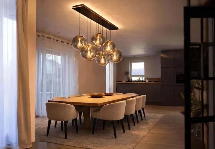 Une table à manger moderne avec des chaises confortables, éclairée par un lustre sphérique, une vraie tendance luminaire.