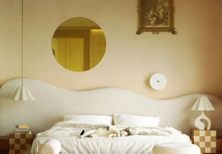 Un chat dort sur un lit douillet. Le beige va avec le blanc, le bois et les touches dorées, créant une ambiance chaleureuse.