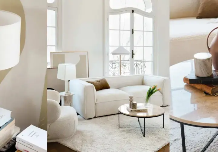 Un salon sans tv, ambiance cosy avec canapé blanc, table basse en marbre et lampes. Des livres et des vases décorent l'espace.
