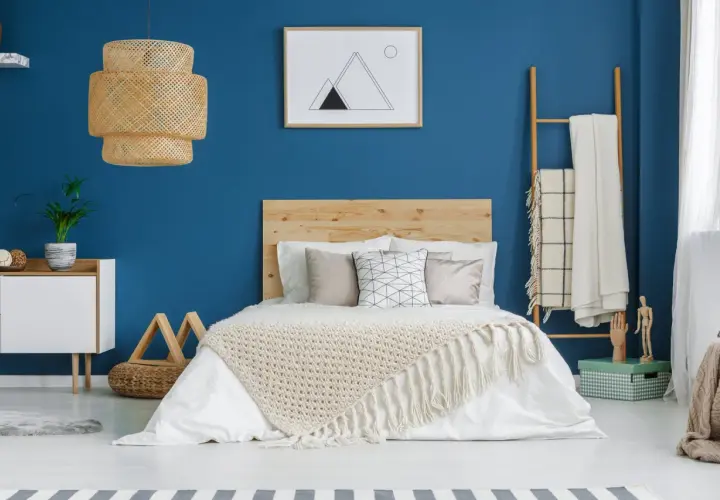 Une chambre bleu et beige avec un lit douillet, une lampe en rotin et une décoration murale minimaliste.