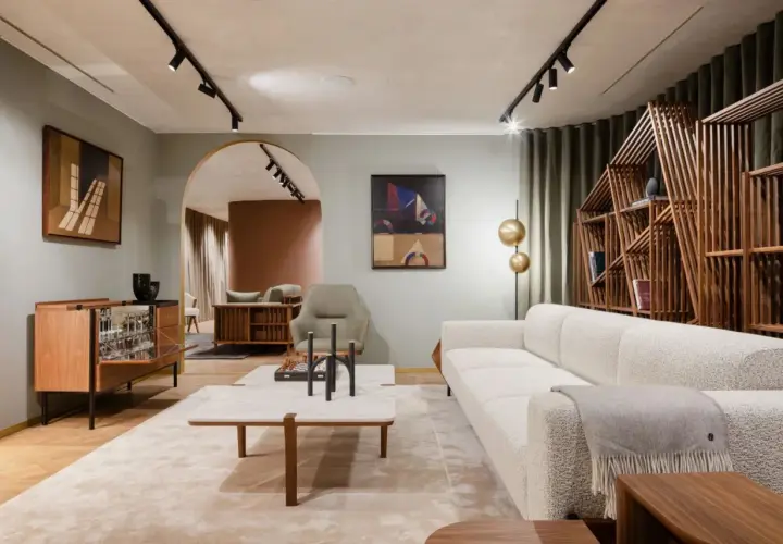 Un salon à la décoration épurée, avec un canapé blanc texturé, une étagère en bois géométrique et des œuvres d'art modernes.