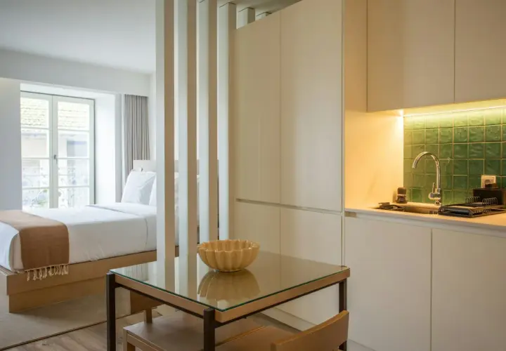 Un studio aménagé pour créer une chambre et une cuisine fonctionnelle. Un lit douillet fait face à une fenêtre, tandis qu'une kitchenette moderne est séparée par des cloisons.
