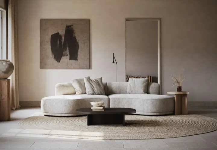 Un **salon écru** aux lignes douces, avec un canapé arrondi, un tapis rond en jonc de mer et une œuvre d'art abstraite.