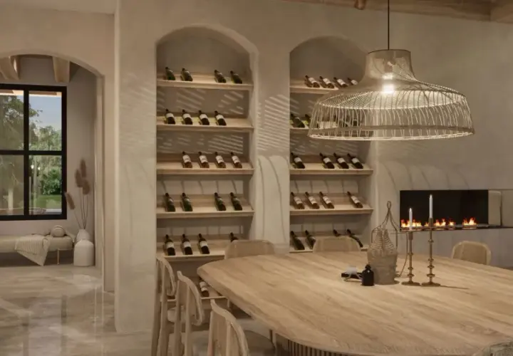 Salle à manger chaleureuse avec une grande table en bois, des étagères à vin remplies, une cheminée et une ambiance deco boho chic.