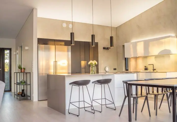 Cuisine lumineuse couleur, avec îlot central, tabourets, réfrigérateur en inox et armoires murales.