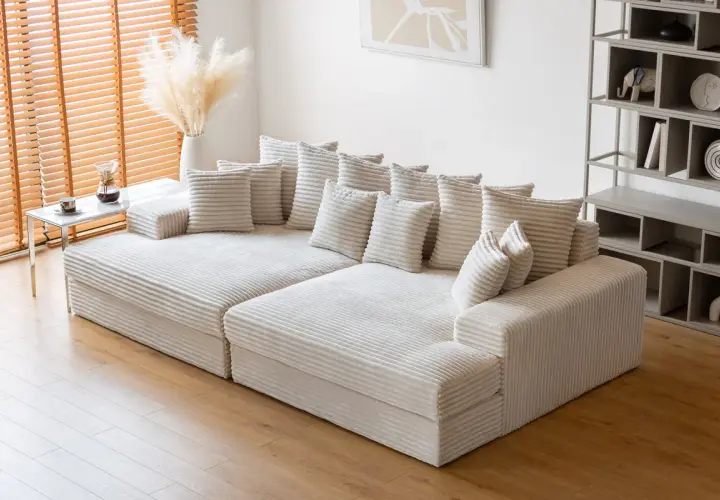 Canapé modulable blanc côtelé, offrant une grande profondeur pour un confort optimal. Des coussins moelleux invitent à la détente.