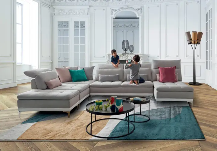 Un salon moderne et lumineux avec un canapé modulable gris, des coussins colorés et un tapis graphique. Une déco séjour tendance pour une famille.