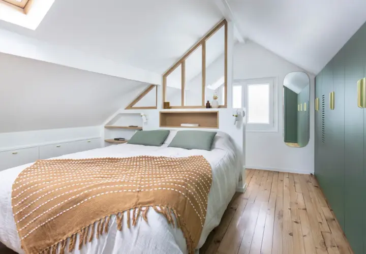 Suite parentale sous comble avec salle de bain et dressing. Un lit douillet, des rangements intégrés et une verrière style verrière d'atelier apportent charme et fonctionnalité.