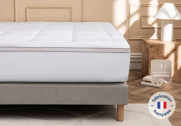 Un surmatelas blanc moelleux sur un sommier gris. Idéal si votre matelas est trop dur que faire ? Fabrication française.