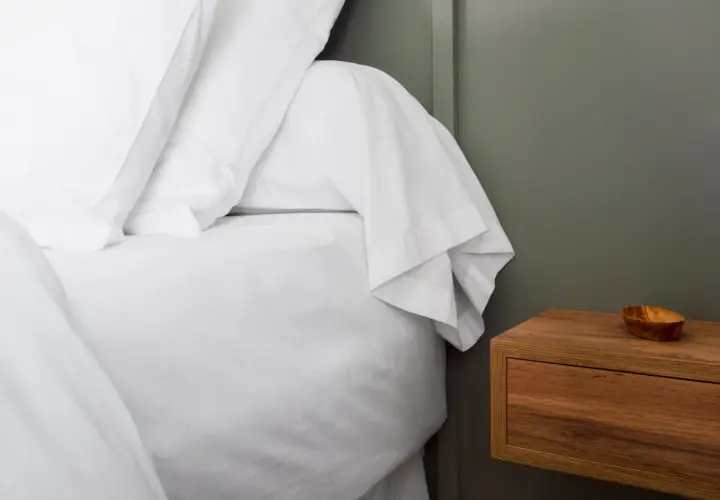 Un lit blanc immaculé avec un drap housse bien ajusté, prêt pour une nuit paisible. C'est quoi un drap housse ? C'est ce qui protège votre matelas.