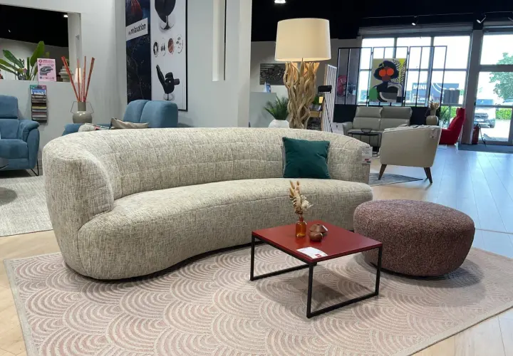 Un canapé courbé et un fauteuil rouge, illustrant la différence entre canapé et fauteuil, dans un showroom de meubles.