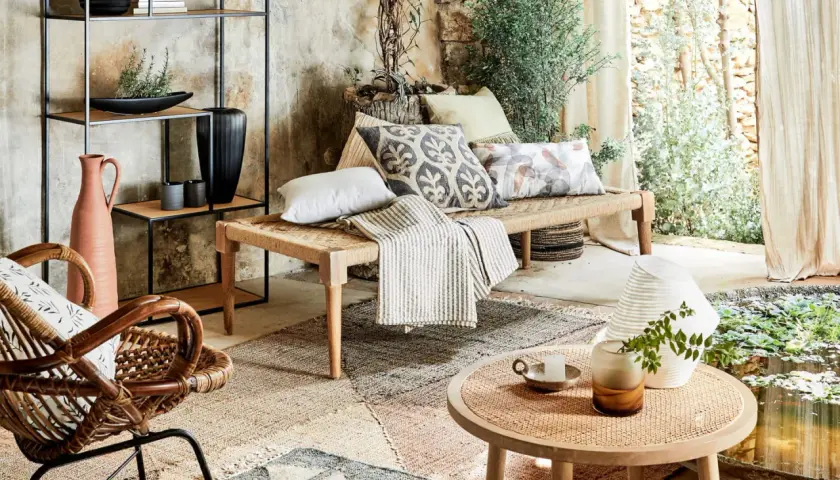 Un canapé moche en corde tressée, orné de coussins décoratifs, dans un salon bohème avec des plantes et une lumière douce.