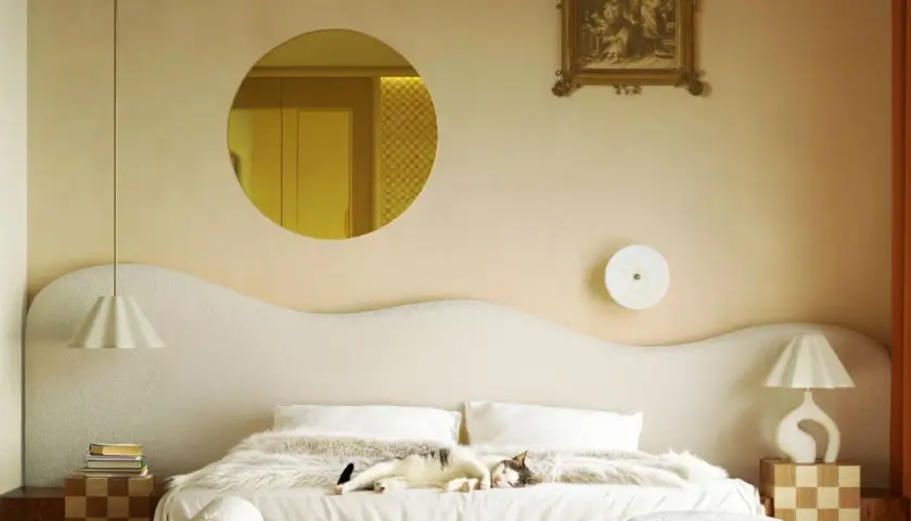 Un chat dort sur un lit douillet. Le beige va avec le blanc, le bois et les touches dorées, créant une ambiance chaleureuse.