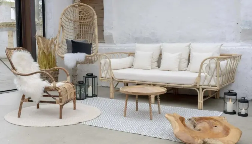 Salon avec une ambiance deco boheme chic. Fauteuil en rotin, canapé blanc, table basse en bois, et un fauteuil suspendu.