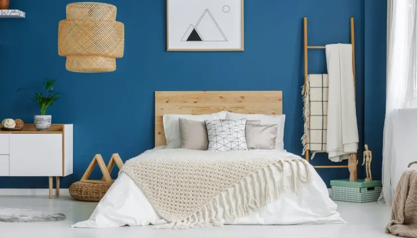 Une chambre bleu et beige avec un lit douillet, une lampe en rotin et une décoration murale minimaliste.