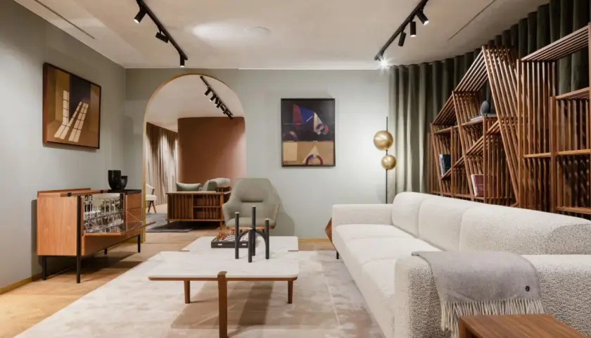 Un salon à la décoration épurée, avec un canapé blanc texturé, une étagère en bois géométrique et des œuvres d'art modernes.