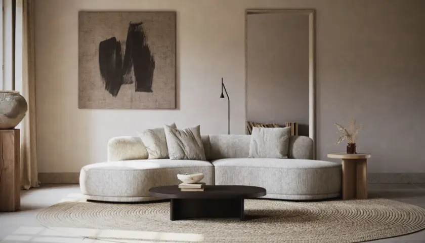 Un **salon écru** aux lignes douces, avec un canapé arrondi, un tapis rond en jonc de mer et une œuvre d'art abstraite.